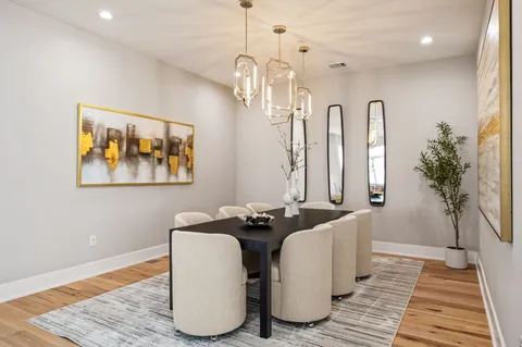 a dining room with wooden floor a chandelier a wooden table and chairs