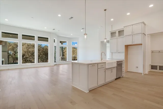 a large kitchen with kitchen island a large window a refrigerator and a sink