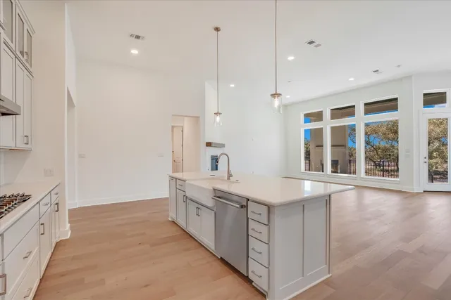 a large white kitchen with granite countertop a sink and dishwasher a stove a refrigerator with wooden floors