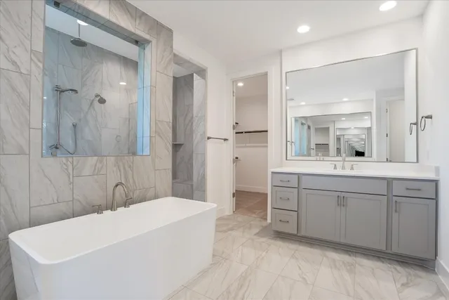 a bathroom with a bathtub a double vanity sink and mirror