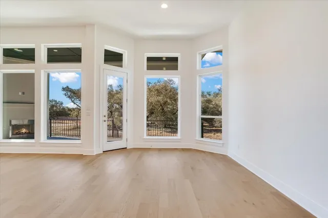 a view of an empty room with a window and wooden floor