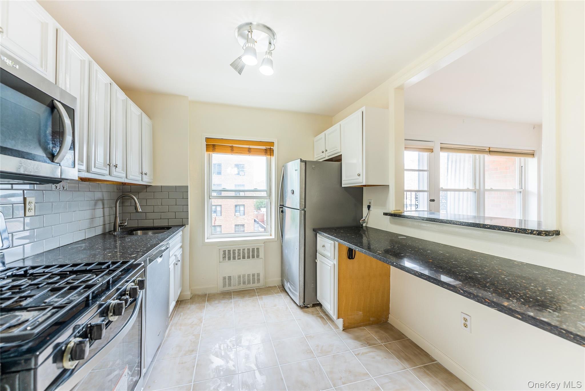 100-26 67th Road, Unit 4F Queens, NY 11375 - Photo 4 of 12 a kitchen with stainless steel appliances granite countertop a stove a sink and a microwave