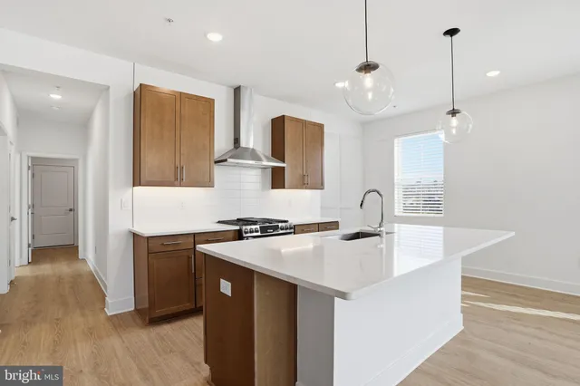 a kitchen with stainless steel appliances granite countertop a sink a stove a refrigerator and island with wooden floor