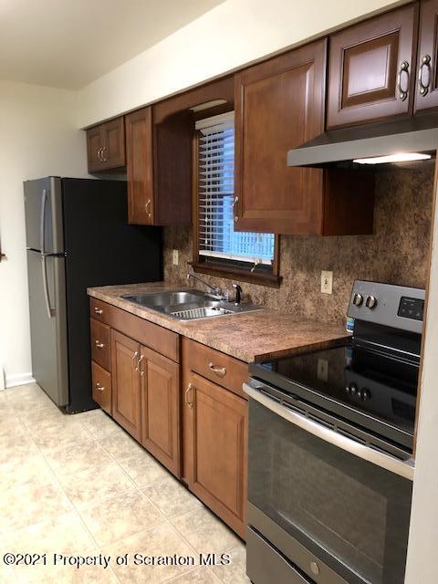 1115 Wheeler Avenue, Unit 1L Dunmore, PA 18510 - Photo 3 of 13 a kitchen with stainless steel appliances granite countertop a refrigerator stove and cabinets