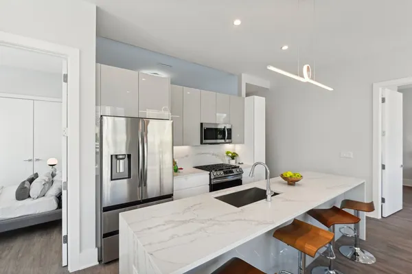 a kitchen with stainless steel appliances a refrigerator a stove a sink a dining table and chairs with wooden floor