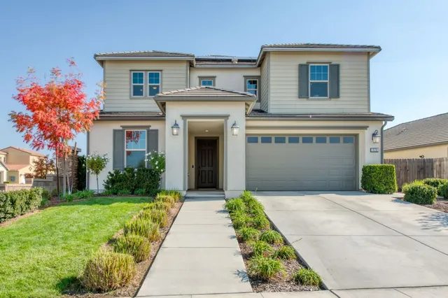 a front view of a house with a yard and potted plants