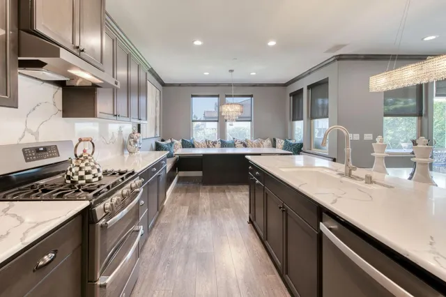 a kitchen with stainless steel appliances kitchen island granite countertop a table chairs stove and refrigerator