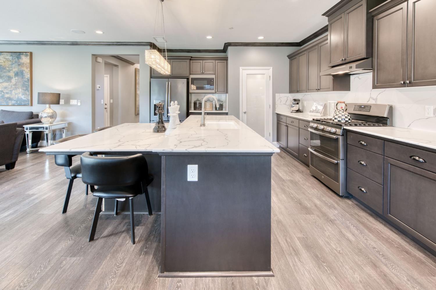 273 Meridian Avenue Madera, CA 93636 - Photo 37 of 55 a kitchen with stainless steel appliances kitchen island granite countertop a table chairs stove and refrigerator