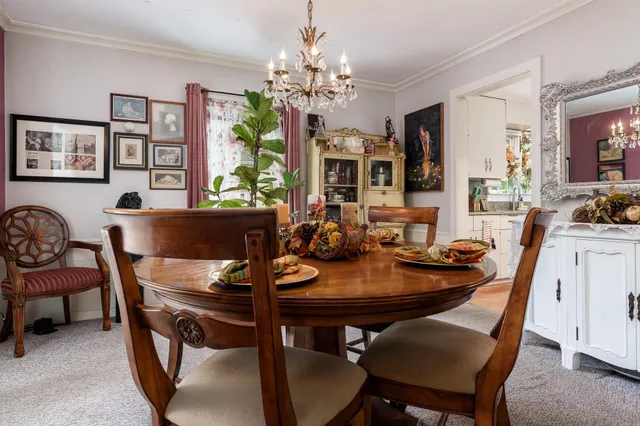 a view of a dining room with furniture a chandelier and a window