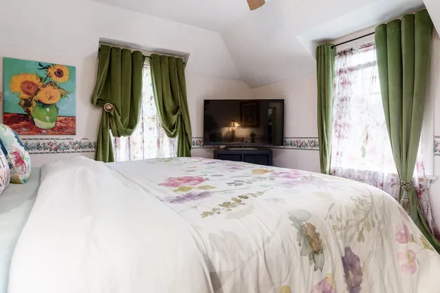 a bedroom with a bed and a flat tv screen on dresser