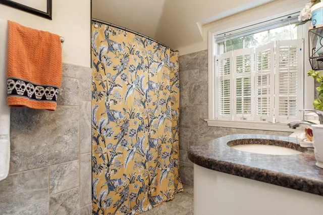 a bathroom with a granite countertop sink and a shower