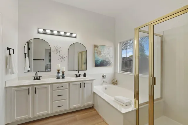 a bathroom with a double vanity sink a mirror and a bathtub