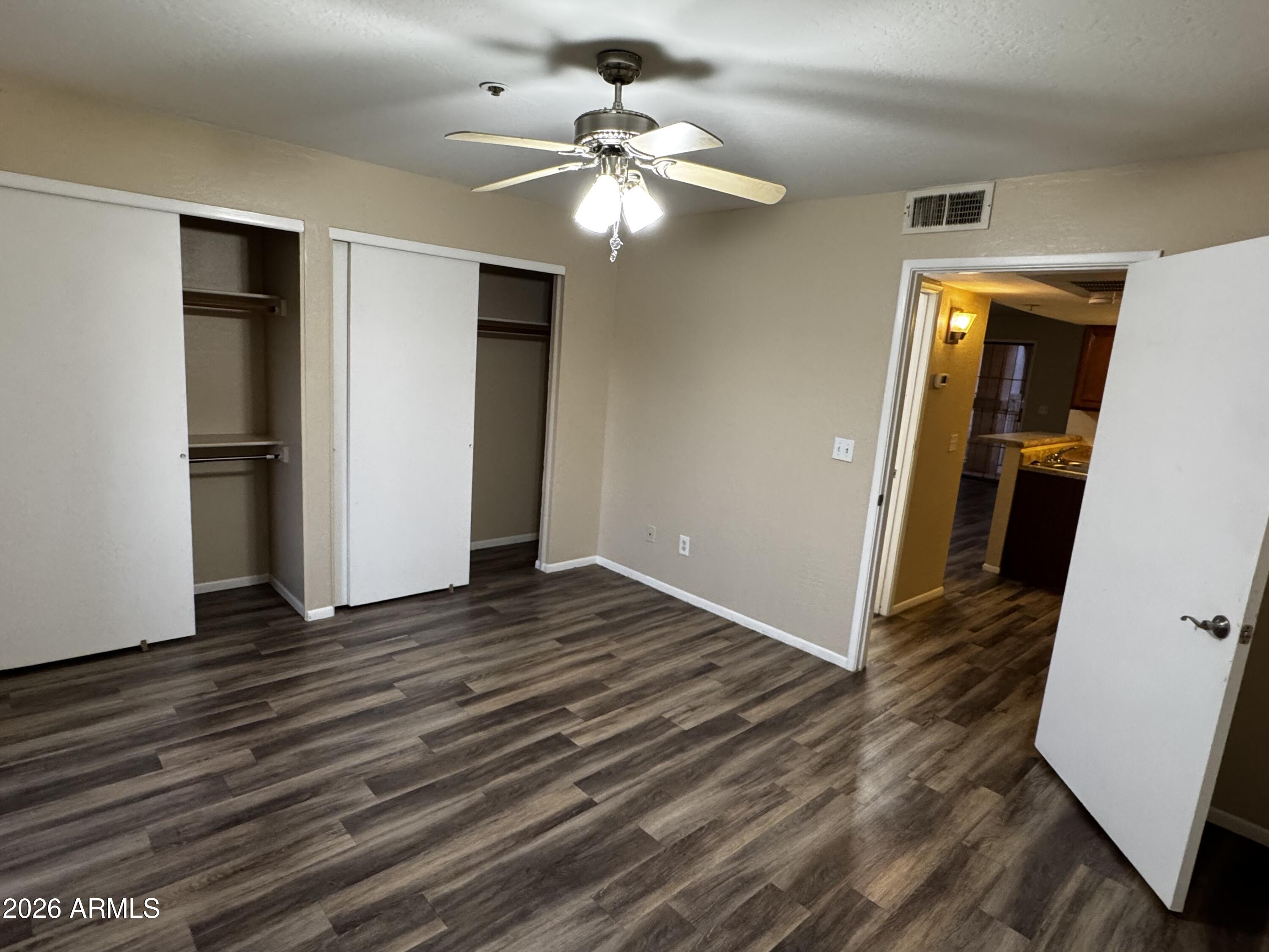 12123 West Bell Road, Unit 258 Surprise, AZ 85378 - Photo 12 of 30 a view of an empty room with wooden floor and a ceiling fan