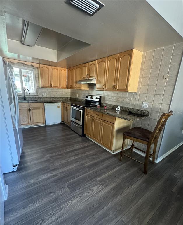 1702 Hickorywood Lane Orlando, FL 32818 - Photo 5 of 8 a kitchen with stainless steel appliances granite countertop a sink wooden cabinets and wooden floor