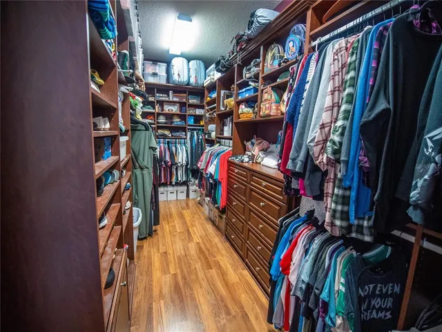 a view of walk in closet with clothes and shoes