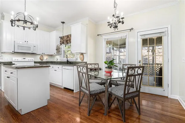 a kitchen with stainless steel appliances granite countertop a stove top oven a dining table and chairs with wooden floor