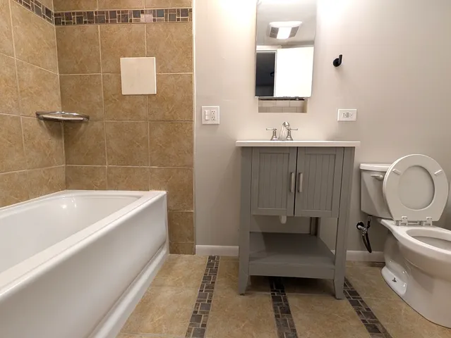 a bathroom with a granite countertop sink a toilet and bathtub