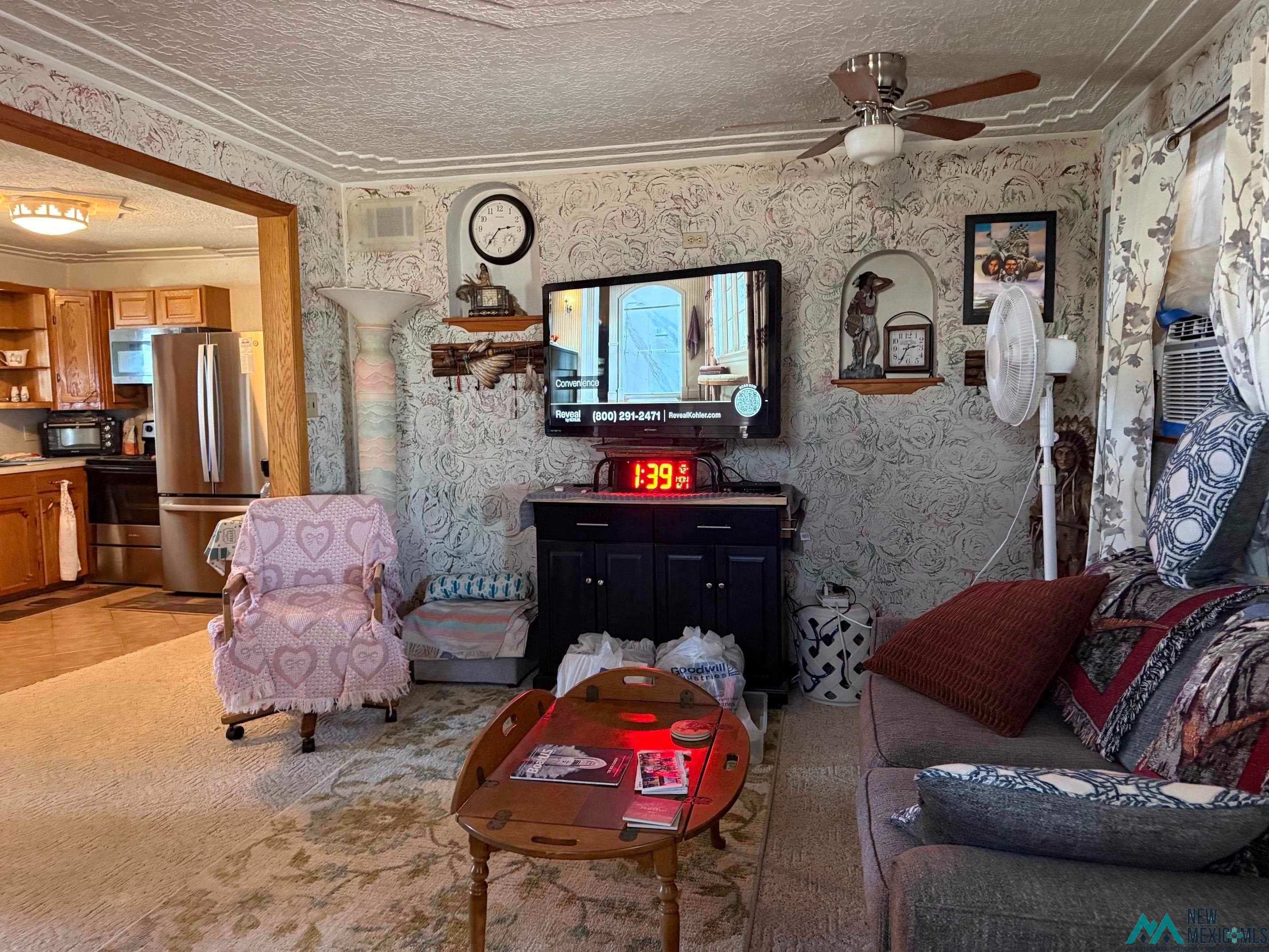 4010 540th Loop Logan, NM 88426 - Photo 4 of 38 Living area with patterned wallpaper, ceiling fan, and carpet flooring
