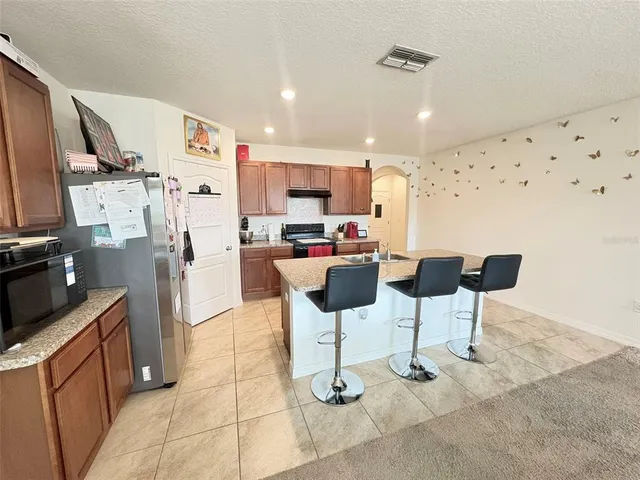 a kitchen with stainless steel appliances kitchen island granite countertop a refrigerator and a stove top oven