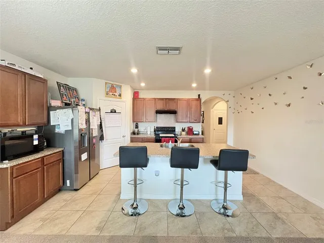 a kitchen with stainless steel appliances kitchen island granite countertop a refrigerator and chairs