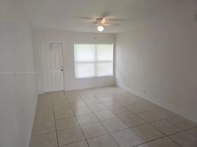 an empty room with white walls and fan