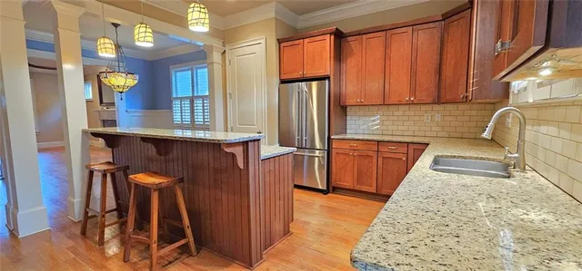 a kitchen with stainless steel appliances granite countertop wooden cabinets a sink and a refrigerator