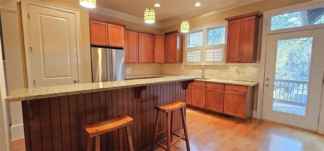 a kitchen with stainless steel appliances granite countertop a refrigerator a sink dishwasher and wooden cabinets with wooden floor