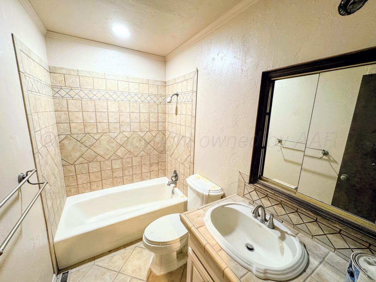 714 South Harvard Street Perryton, TX 79070 - Photo 12 of 27 a bathroom with a sink a toilet a mirror a bathtub and shower