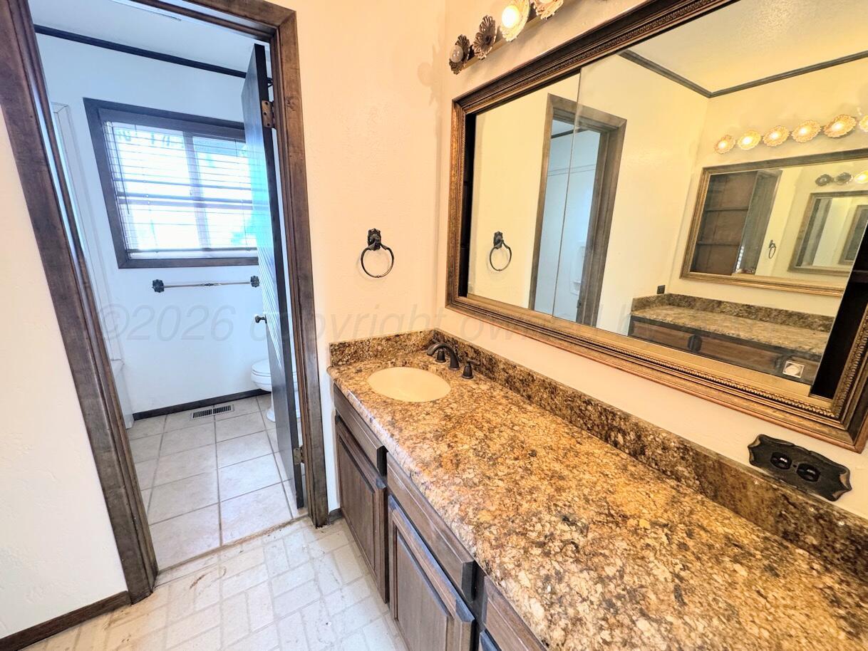 714 South Harvard Street Perryton, TX 79070 - Photo 7 of 27 a bathroom with a granite countertop sink and a mirror