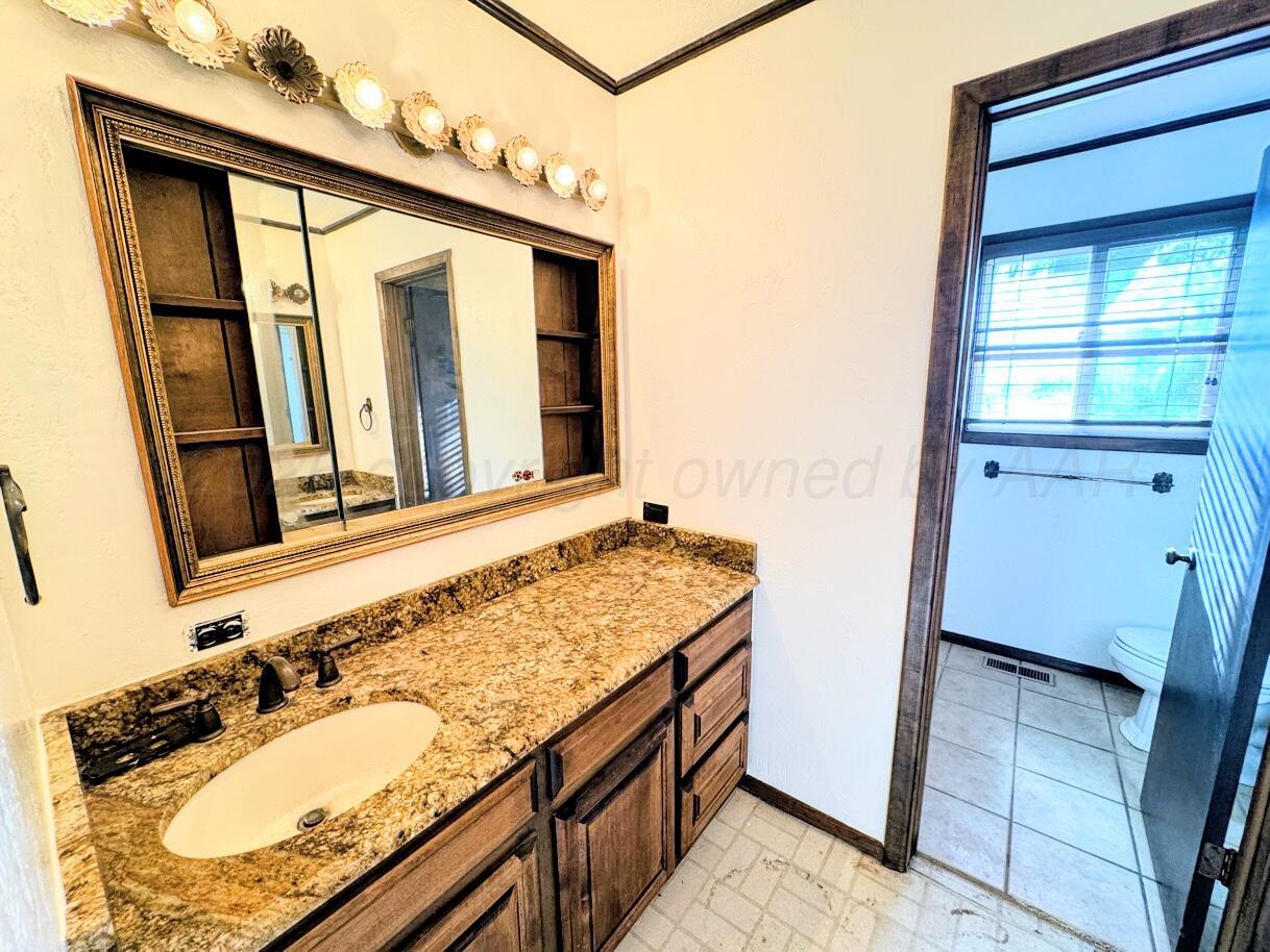 714 South Harvard Street Perryton, TX 79070 - Photo 8 of 27 a bathroom with a granite countertop sink and a mirror