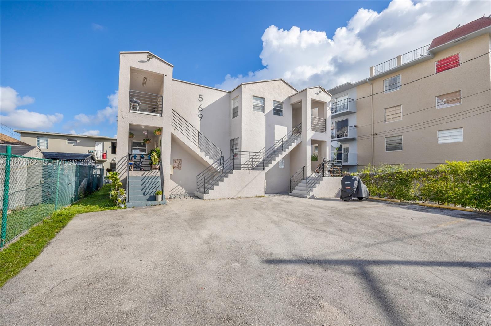 a view of a white building among the street with palm trees