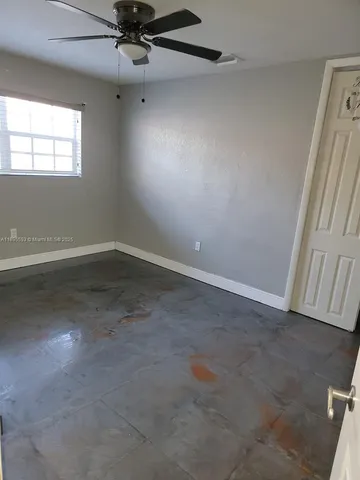 an empty room with a ceiling fan and window