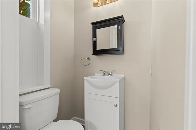 a bathroom with a toilet sink vanity and mirror
