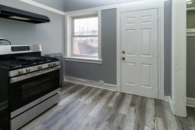 a view of kitchen with wooden floor electronic appliances and cabinets