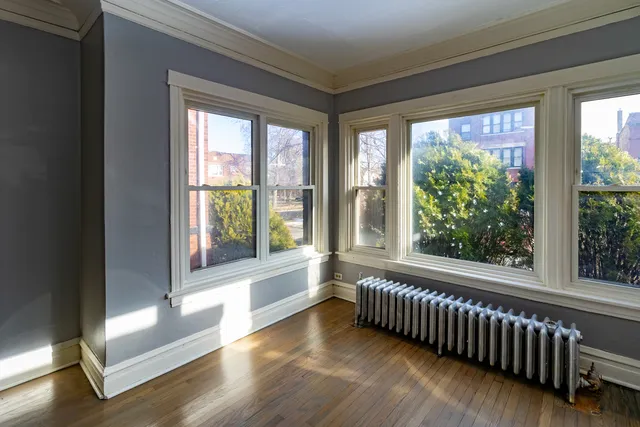 a view of an empty room with wooden floor fireplace and a window