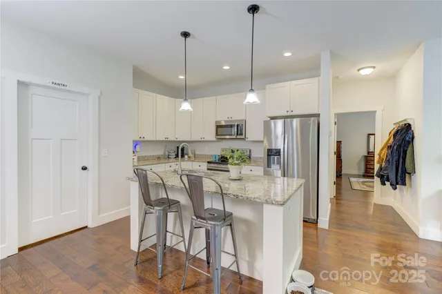 a view of a dining room and livingroom with furniture wooden floor a chandelier