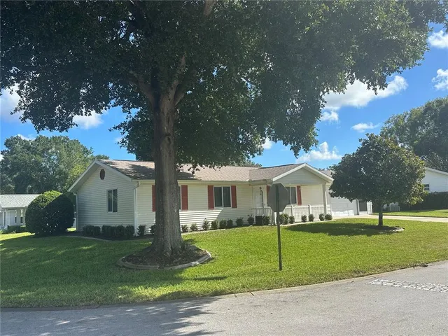 a view of house with a big yard and large trees