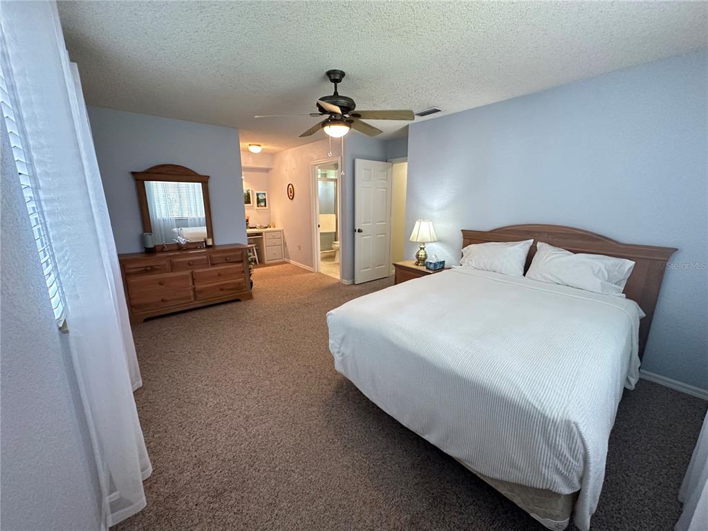 8981 Southwest 116th Street Road Ocala, FL 34481 - Photo 19 of 28 a bedroom with a large bed and a chandelier