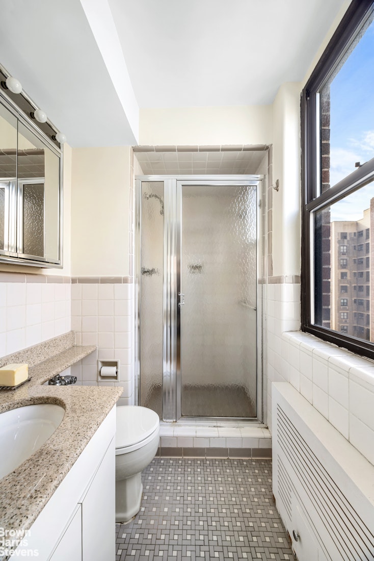 239 East 79th Street, Unit 12P Manhattan, NY 10075 - Photo 7 of 9 a bathroom with a granite countertop sink a toilet a mirror and shower