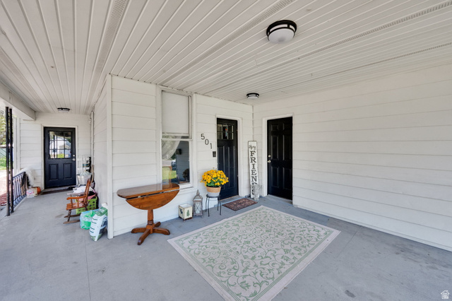 501 Canyon Road Ogden, UT 84404 - Photo 8 of 30 Covered front porch featuring two black paneled entry doors, white siding, a window with white trim, and overhead lighting