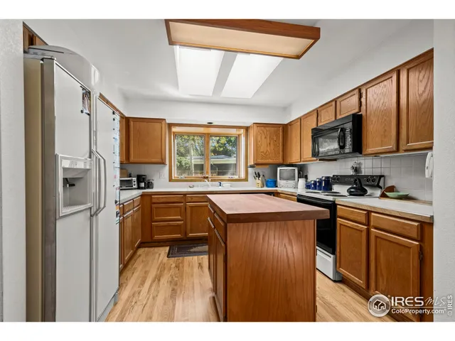 a kitchen with stainless steel appliances granite countertop a refrigerator a sink dishwasher a stove and white countertops with wooden floor