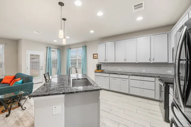 a kitchen with granite countertop kitchen island stainless steel appliances a sink and cabinets