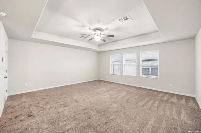 an empty room with chandelier fan and windows