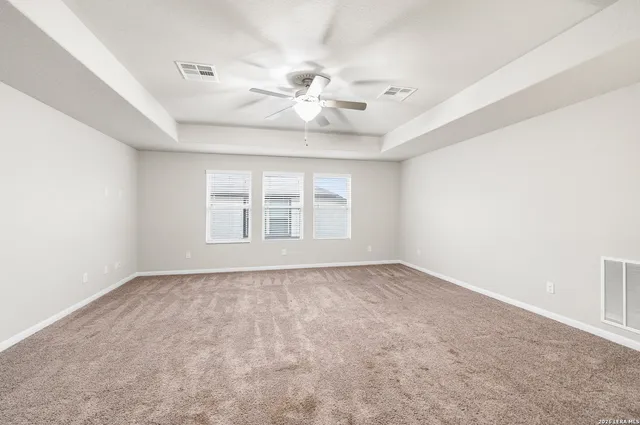 an empty room with windows and fan