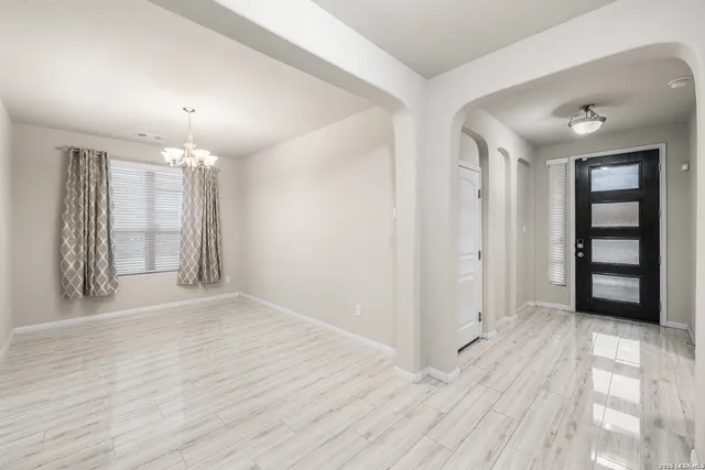 a view of an empty room with window and wooden floor