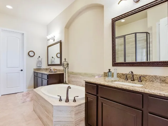 a bathroom with a tub a double vanity sink and mirror