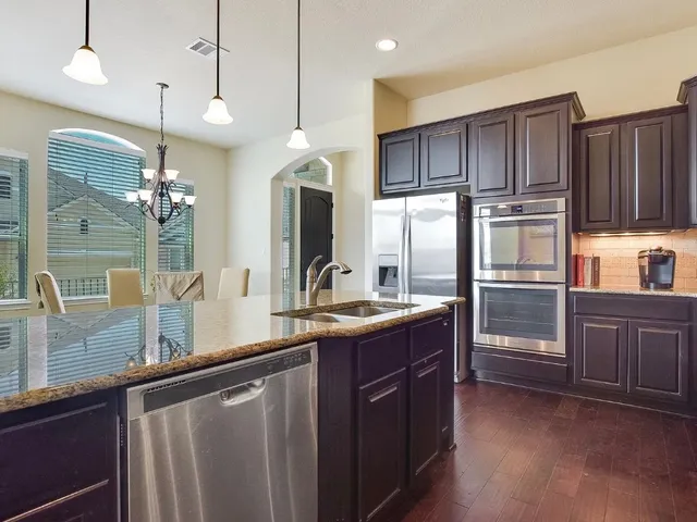 a kitchen with kitchen island granite countertop stainless steel appliances and wooden cabinets
