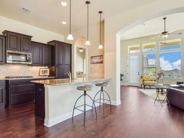 a kitchen with stainless steel appliances granite countertop wooden floors stove refrigerator dining table and chairs