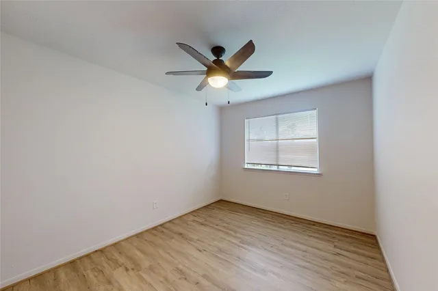 a view of an empty room with window and ceiling fan