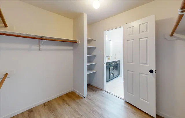 a view of an empty room with closet and wooden floor